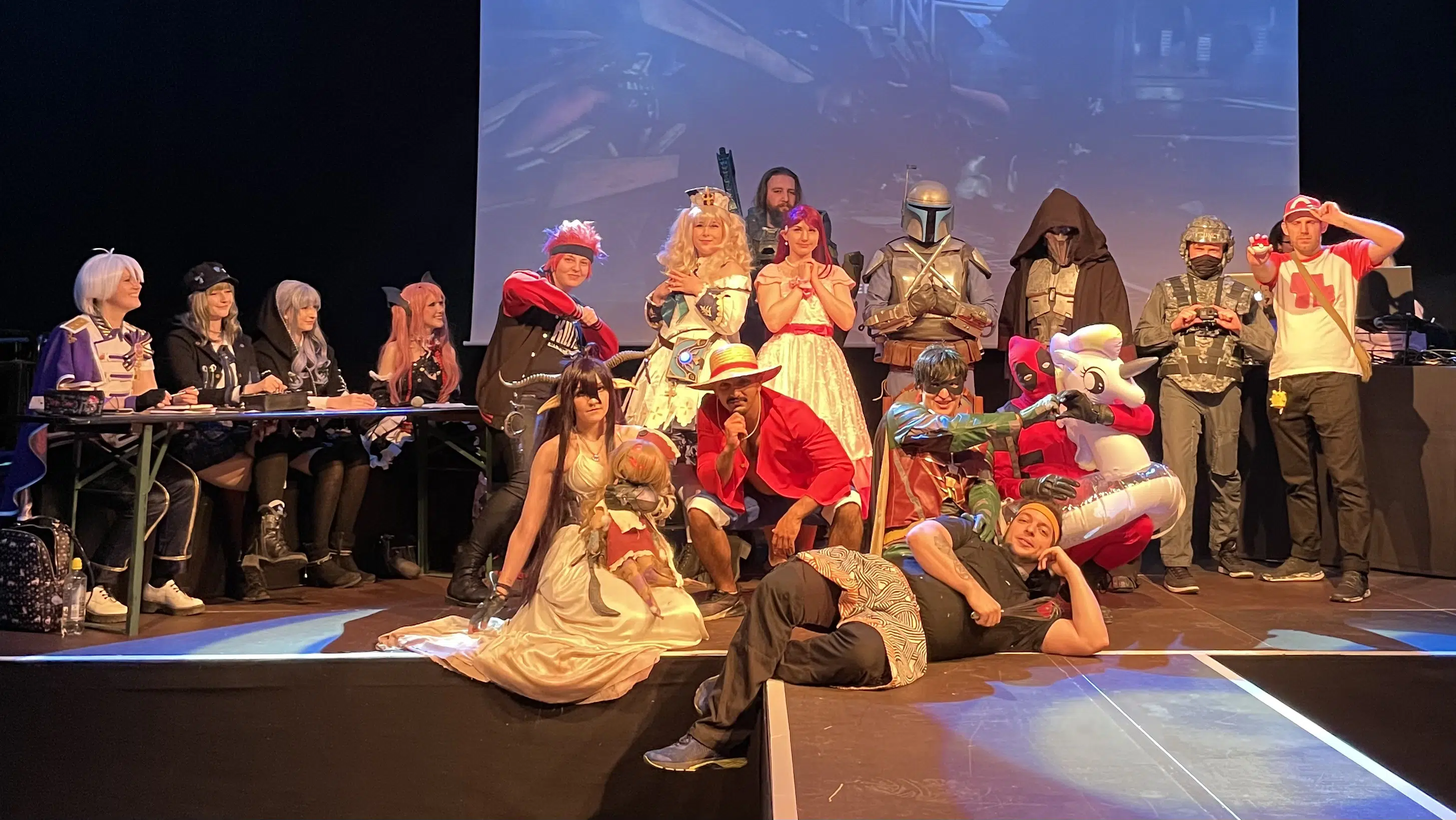 17 Cosplayer auf der Bühne des Feierwerk im Gruppenbild der Teilnehmer des Kaizoku Cosplay Contest.